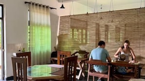 Un comedor con una mesa redonda, sillas de madera y un ventilador de techo.