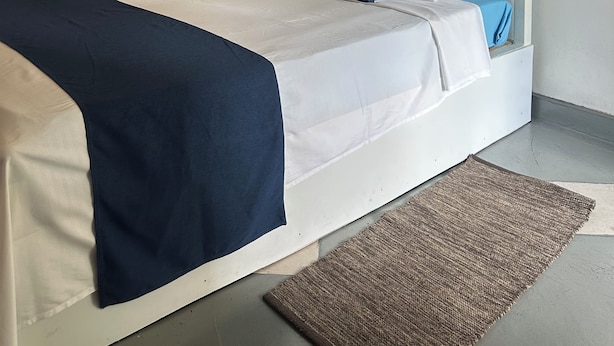 Habitación de hotel con una cama, una lámpara fijada a la pared y un adorno circular grande en la pared.