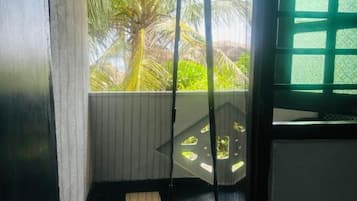 Ein Zimmer mit Blick auf Palmen, ein Fenster mit Gittermuster und ein Boden mit Schachbrettdesign.