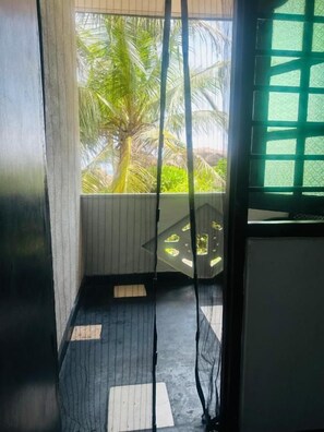 A room with a view of palm trees, a window with a grid pattern, and a floor with a checkered design. - Rock Hill Hotel - Unawatuna (Unawatuna)