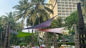 A hotel courtyard with outdoor seating, palm trees, and a building in the background.