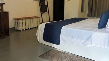 A hotel room with a bed, a bench, a ladder, a wall with geometric patterns, and a door.