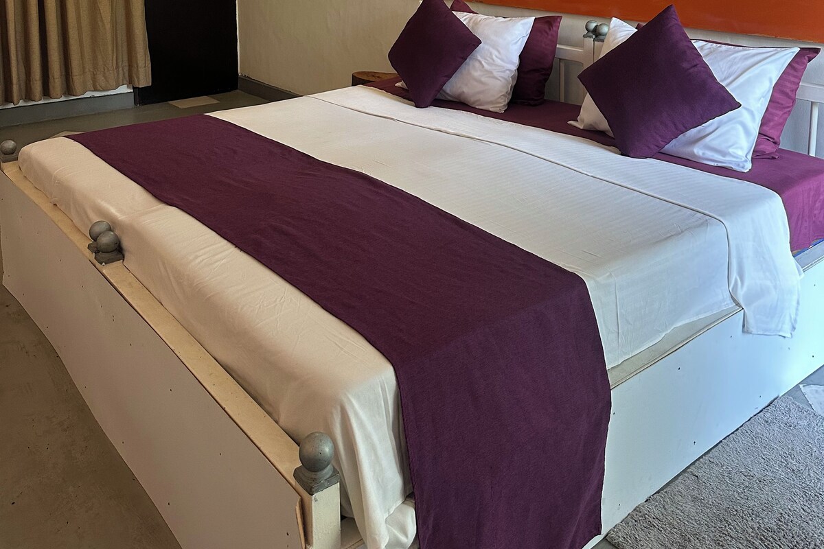 A hotel room with a large bed, a headboard with circular designs, and a wall-mounted light fixture.