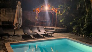 En pool med solstolar och ett avskärmat sittområde.