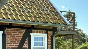 Ein Backsteinhaus mit Ziegeldach, einem Fenster und einem Tisch mit Stühlen vor der Tür.
