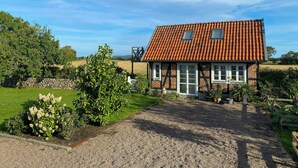 Ein Haus mit rotem Ziegeldach, einem Schotterweg und einem Garten mit verschiedenen Pflanzen.