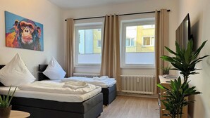A modern bedroom with a bed, two bedside tables, a chair, a radiator, and a large window. - Stylish Flat • Central • 6 Guests • 65sqm (Hanover)