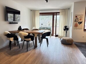 Un comedor moderno con una mesa de madera, sillas negras y un taburete redondo.