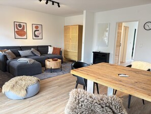 Ein modernes Wohnzimmer mit einer Couch, einem runden Couchtisch und einem Esstisch mit Stühlen.