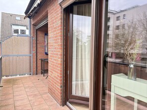 Ein Wohngebäude mit Backsteinfassade, einer Schiebetür aus Glas und einer gefliesten Terrasse.