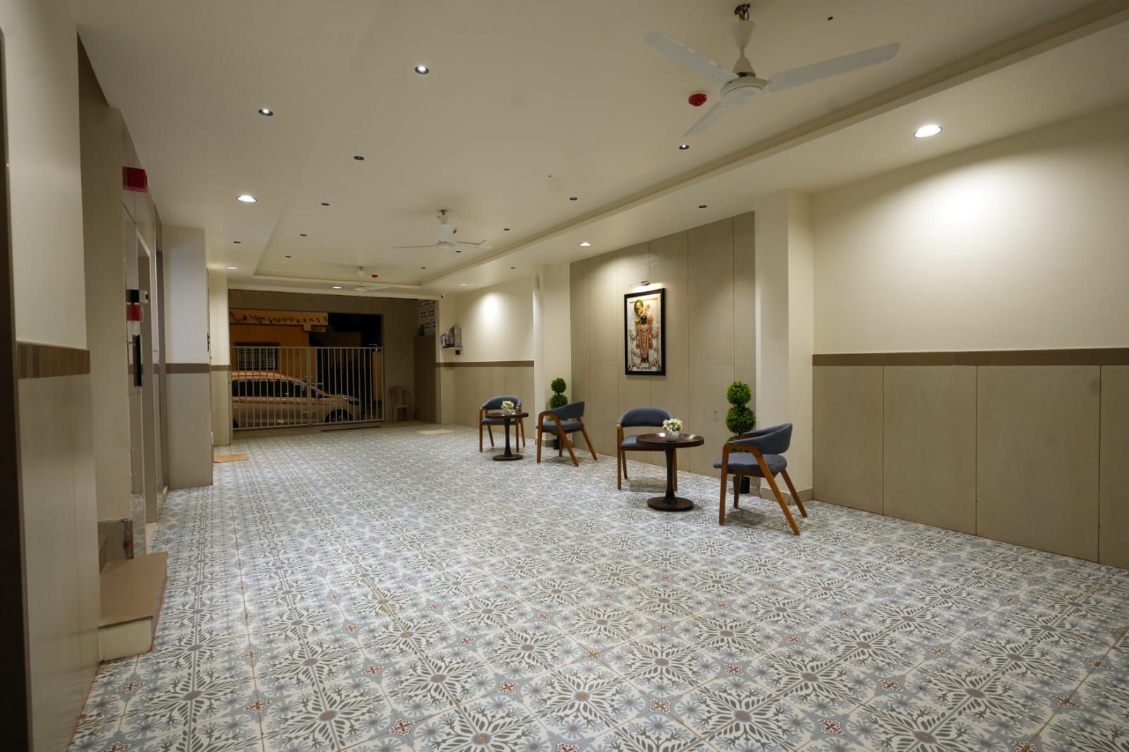 Un pasillo de hotel con piso estampado, ventiladores de techo, iluminación empotrada y zonas de estar.