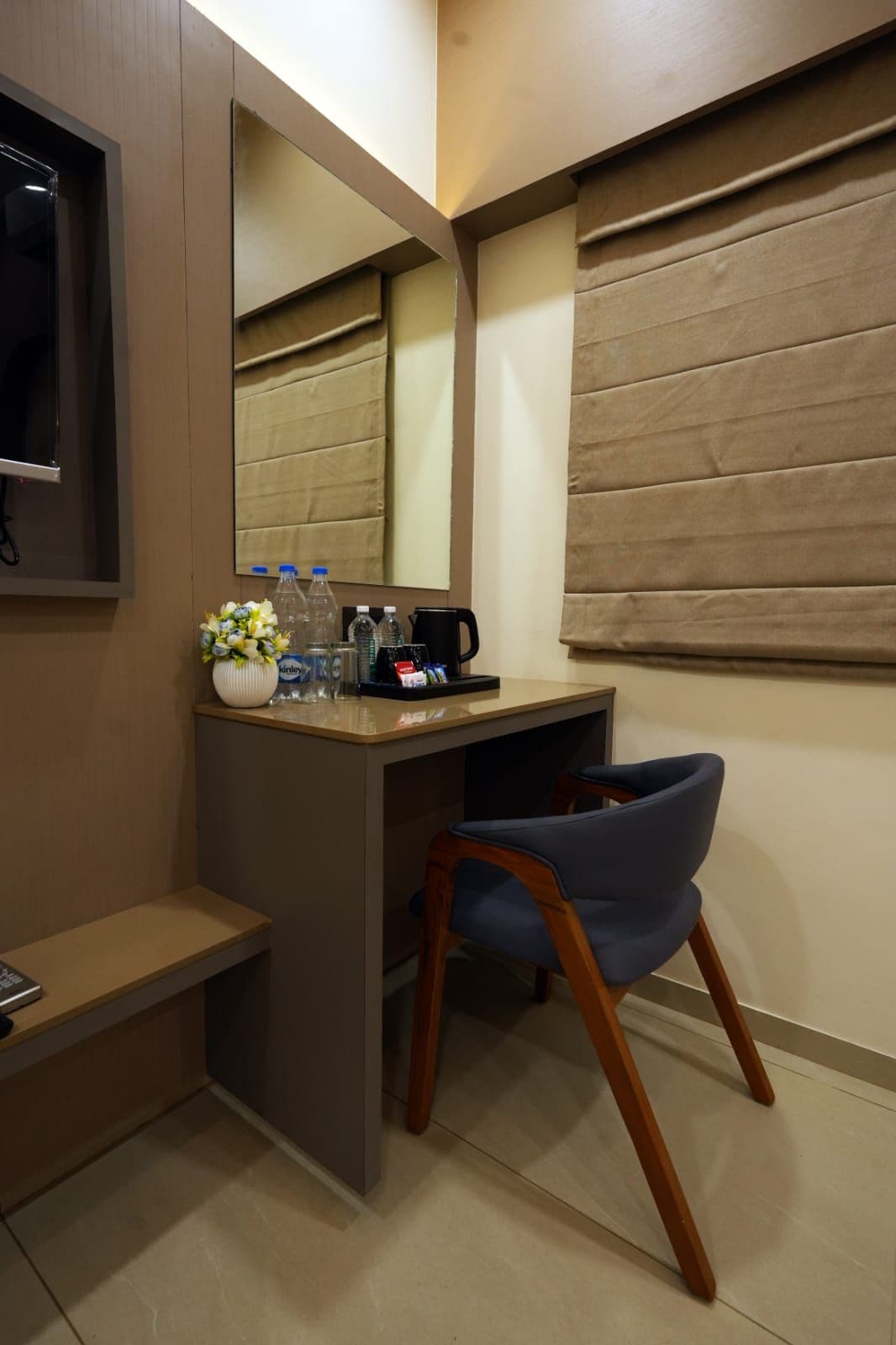 Una habitación pequeña y moderna con un escritorio, una silla y un espejo grande.
