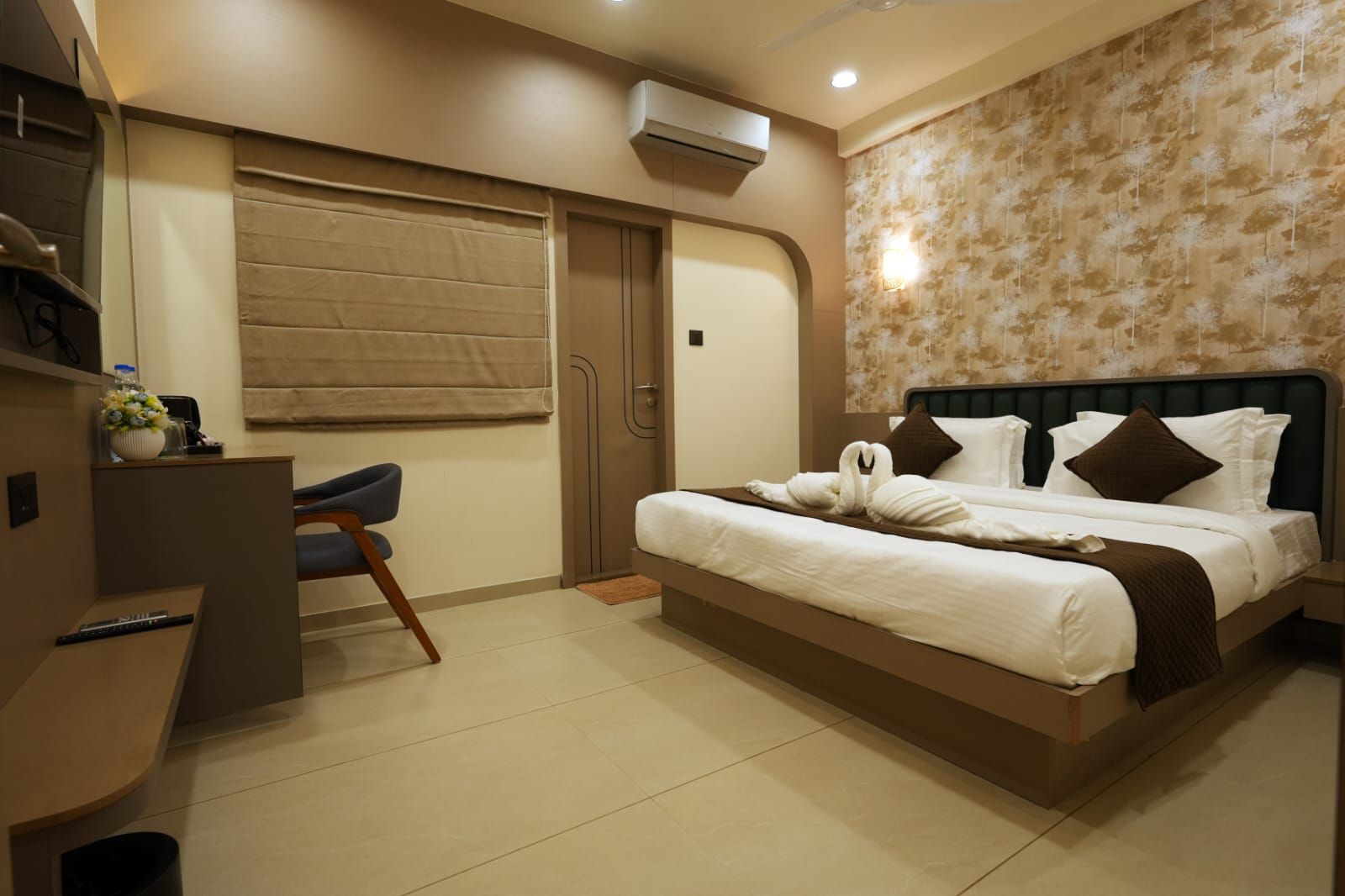 Habitación de hotel con cama, escritorio, silla y ventana con persiana.