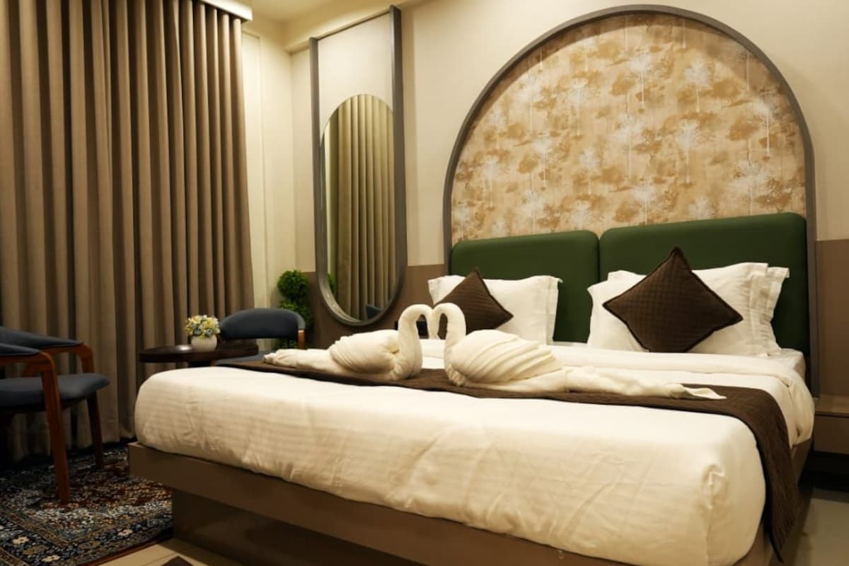 A modern hotel room with a large bed, a round headboard, a ceiling fan, and a view of the outdoors.