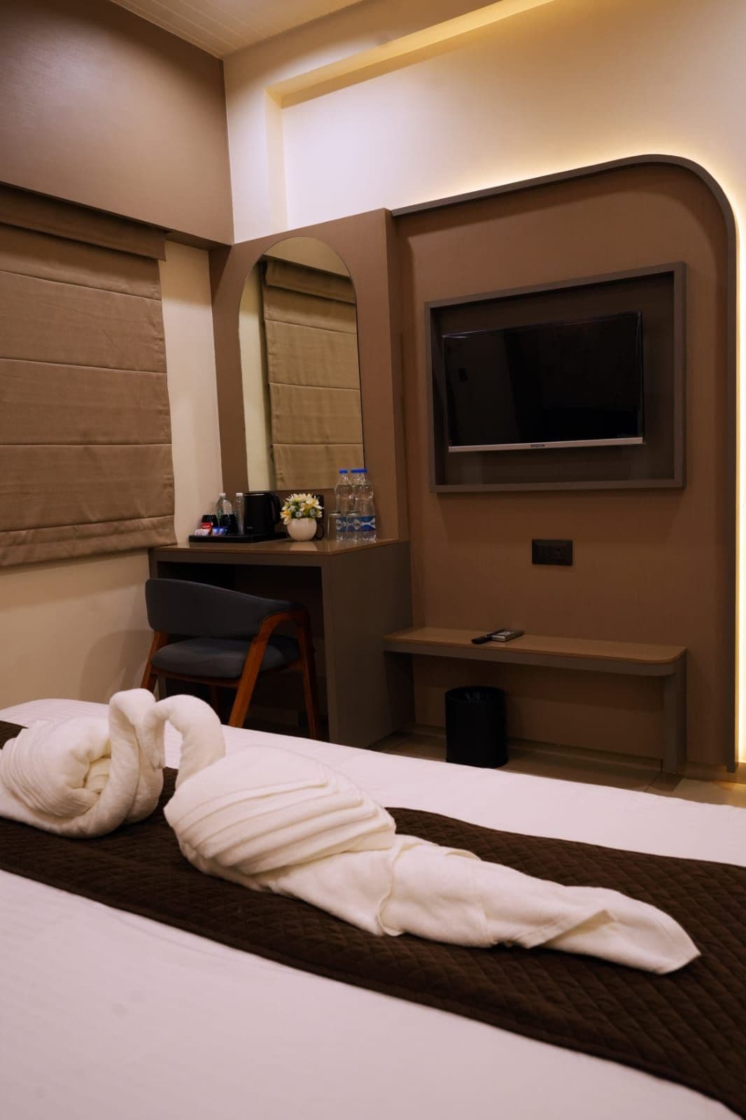 Ein Hotelzimmer mit einem Bett, einem Schreibtisch, einem Sessel, einem Fernseher und einem Spiegel.