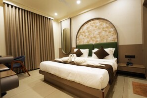 A hotel room with a large bed, a desk, and a chair. - Hotel The Dwarka palace (Dwarka)
