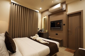 A hotel room with a bed, a TV, a mirror, and a wardrobe. - Hotel The Dwarka palace (Dwarka)