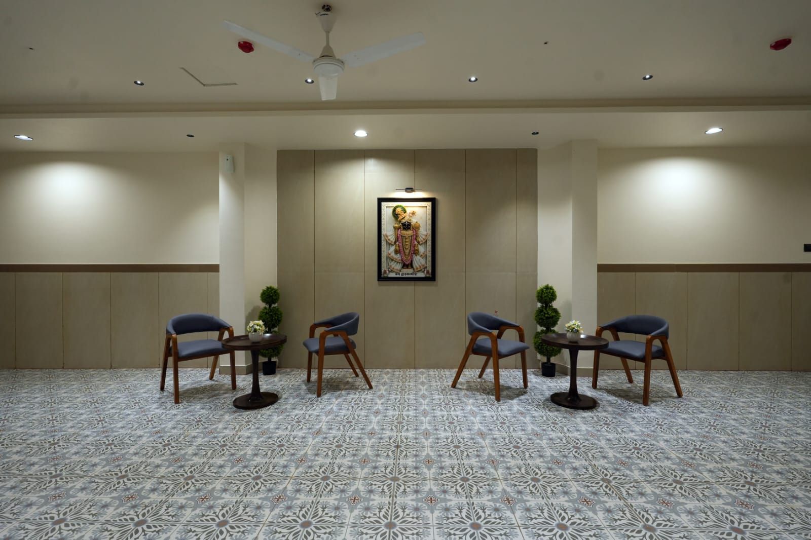 A conference room with a patterned carpet, wooden chairs, a ceiling fan, recessed lighting, and a framed picture on the wall.