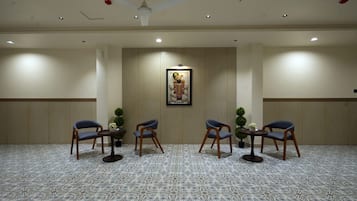 A conference room with a patterned carpet, wooden chairs, a ceiling fan, recessed lighting, and a framed picture on the wall.