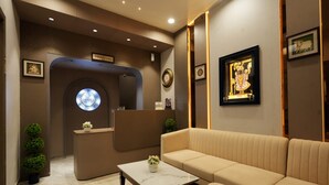 En modern hotellobby med en receptionsdisk, en soffa och ett soffbord.