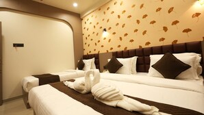 Ett hotellrum med två sängar, en sänggavel med ett bladmotiv och en väggmonterad lampa.