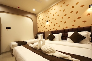 A hotel room with two beds, a headboard with a leaf pattern, and a wall-mounted light fixture. - Hotel The Dwarka palace (Dwarka)