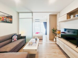 A modern living room with a sofa, coffee table, and television. - Modern New 1 BR Condo(BWC2) (Hua Hin)