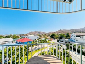 A balcony with a view of a residential area, including houses and a road. - Modern New 1 BR Condo(BWC2) (Hua Hin)