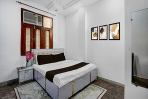 A bedroom with a bed, a nightstand, a window with curtains, and wall art. - Hotel O Golden Key Rohini (New Delhi)