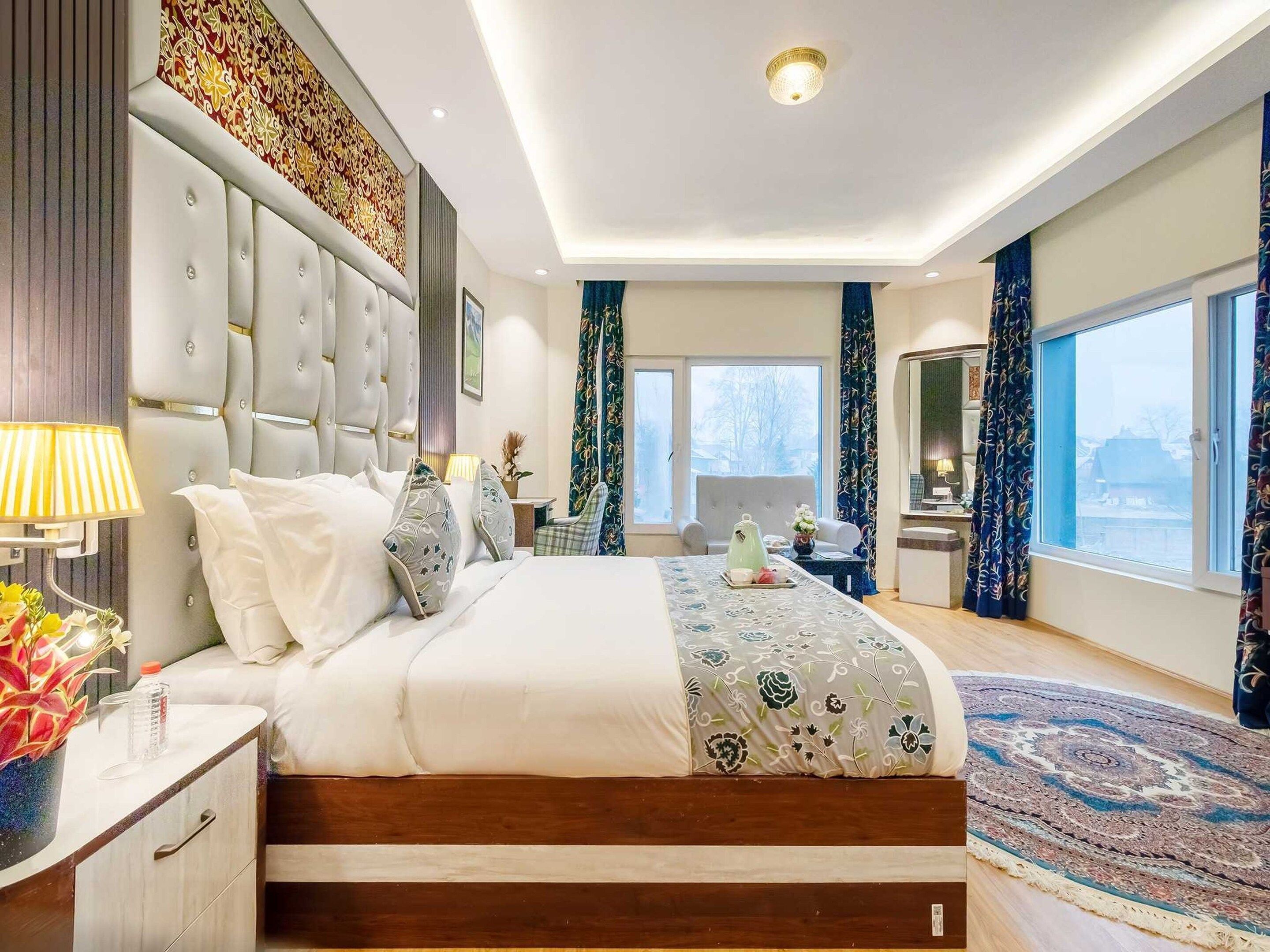 A modern bedroom with a large bed, a bedside table, a nightstand, a desk, and a chair.