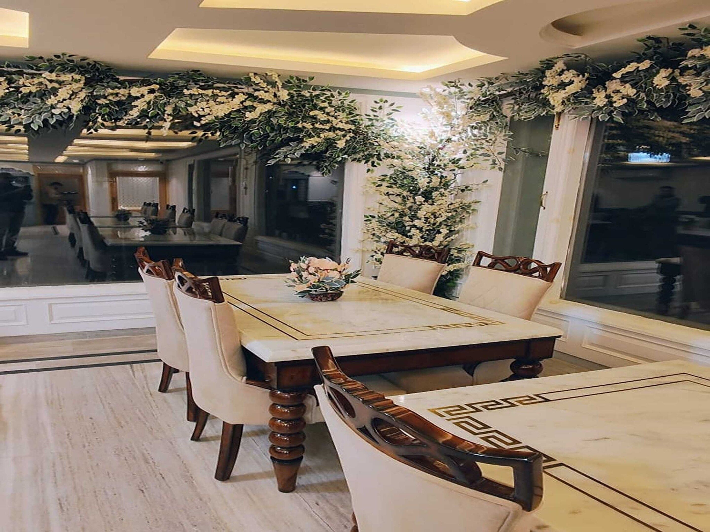 A dining area with a large table, chairs, and a decorative floral arrangement.