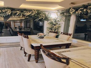 Comedor con una mesa grande, sillas y un arreglo floral decorativo.