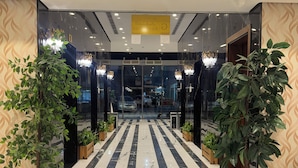 En hotellentrén med ett marmorgolv, krukväxter och en kristallkrona.