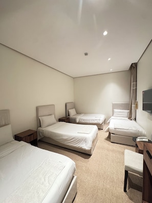 A hotel room with three beds, a desk, a chair, and a television. - Shaza Asil Hotel (Makkah)