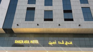 A hotel building with a modern facade, large windows, and a sign indicating it is the ShaZa Asil Hotel.