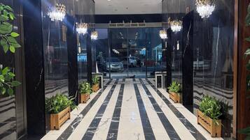 Eine Hotelhalle mit Marmorboden, Zimmerpflanzen, Kronleuchtern und einer Rezeption.