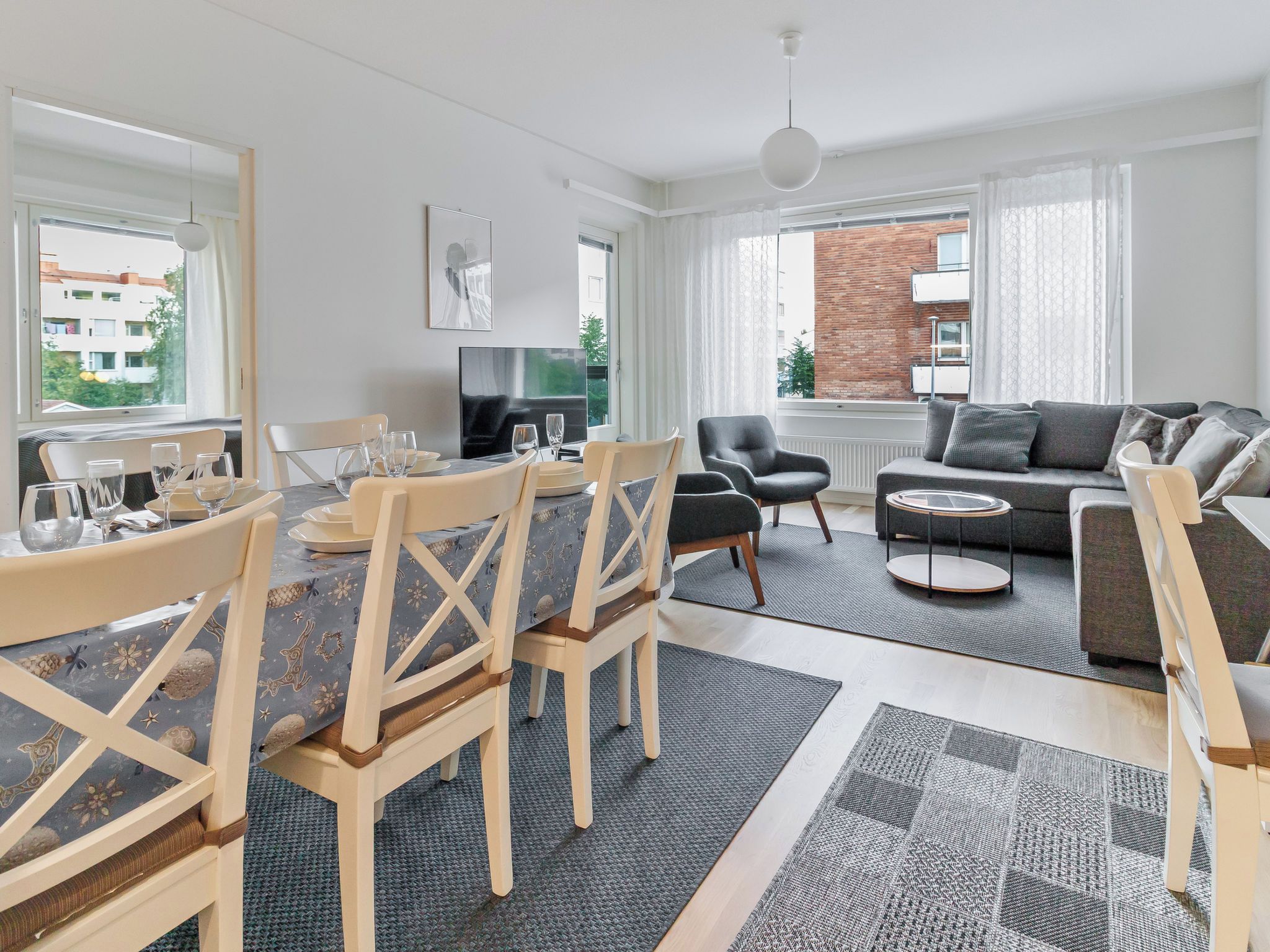 A modern living room with a dining area, a sofa set, and a TV.