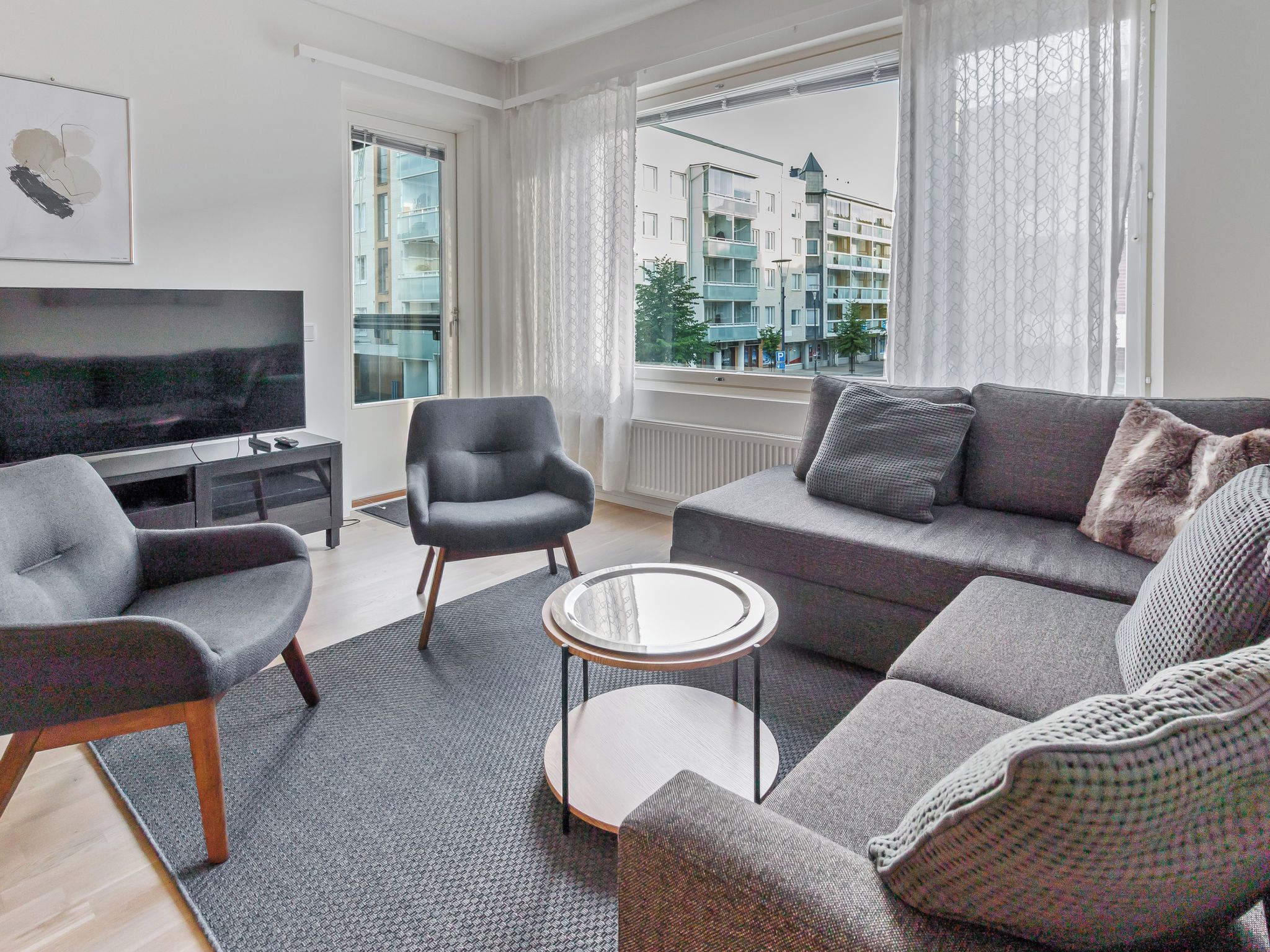 Una sala de estar moderna con un sofá, sillones, una mesa de centro y un televisor.