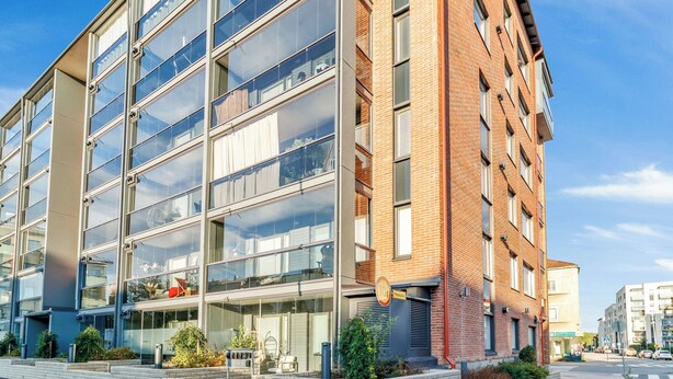 Ein modernes Gebäude mit mehreren Stockwerken, großen Fenstern und einer Ziegel-Fassade.