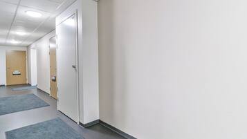 A corridor with doors, carpeted floors, and a ceiling with recessed lighting.