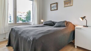 Ein Schlafzimmer mit einem Bett, einem Nachttisch, einer Lampe und zwei gerahmten Bildern an der Wand.
