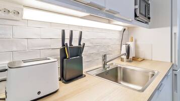 A modern kitchen with a built-in toaster, a knife block, a sink, and a microwave.
