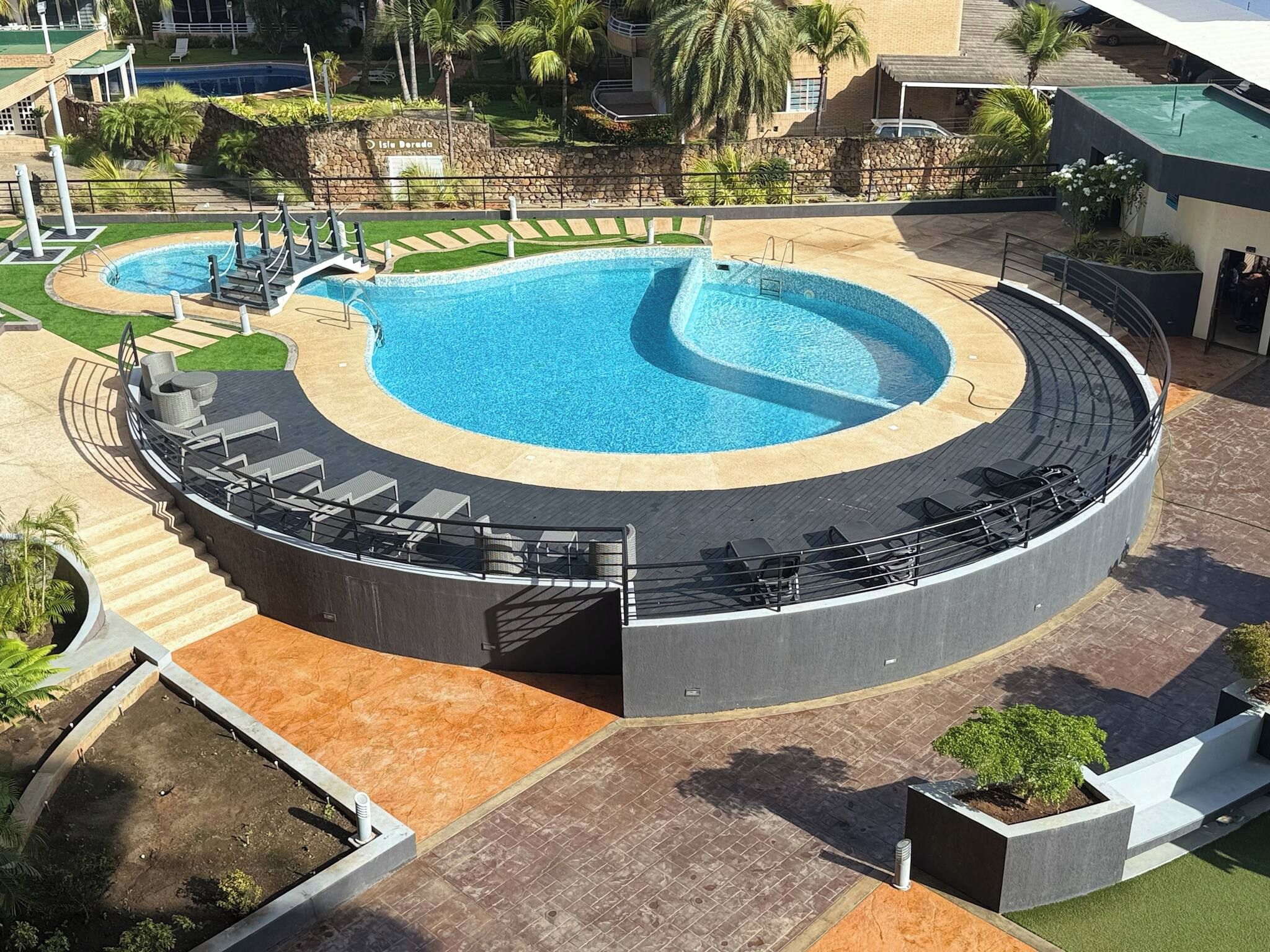 Una piscina circular con un borde pavimentado y sillones de descanso.