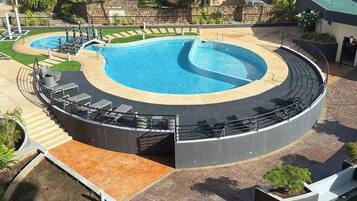 Una piscina circular con un borde pavimentado y sillones de descanso.