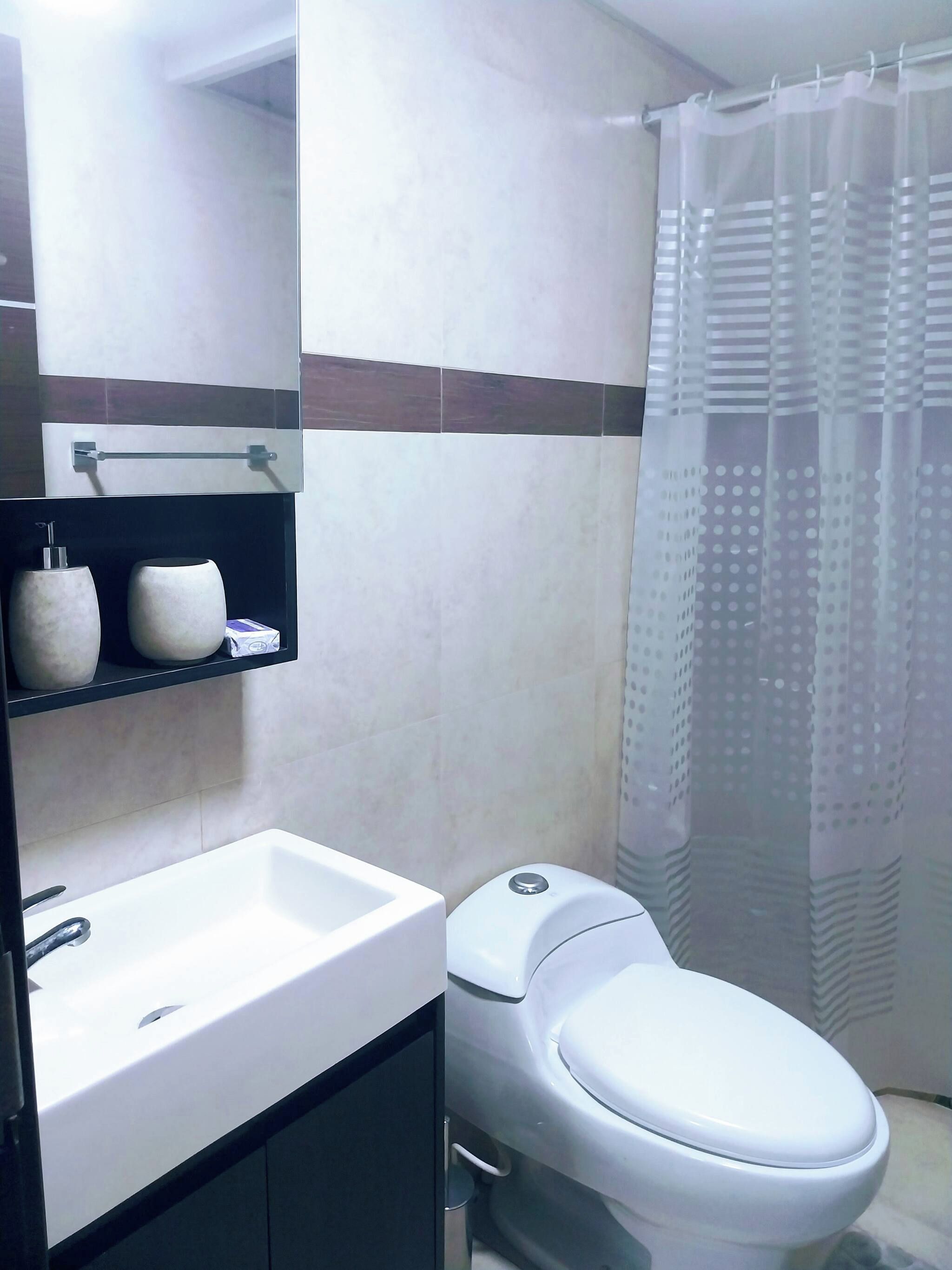 Un baño con lavamanos blanco, inodoro y cortina de ducha.