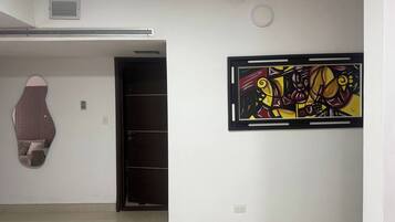 A room with a large abstract painting on the wall, a door, and a patterned object on the wall.