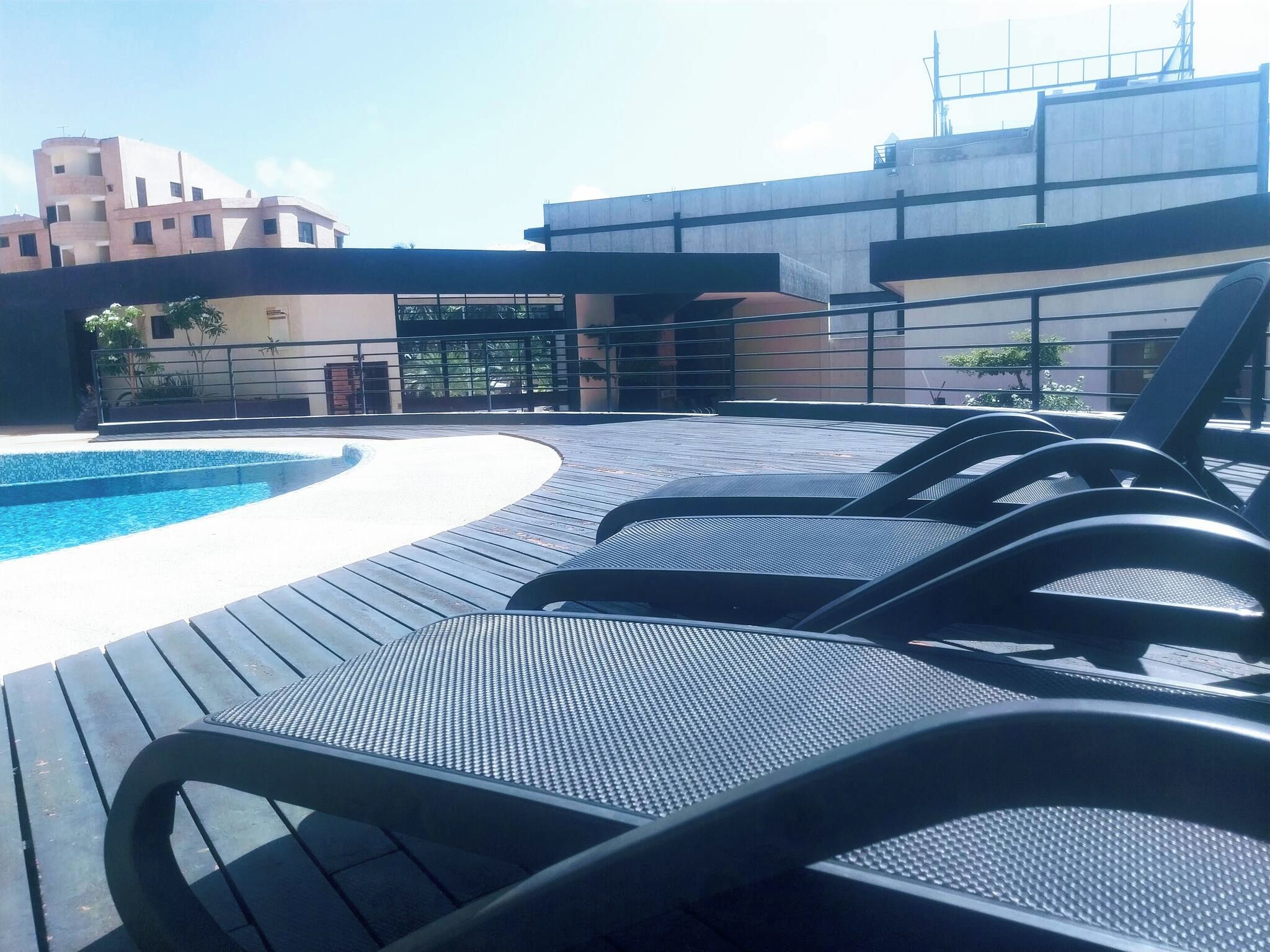 Zona junto a la piscina con sillones de descanso y una piscina.