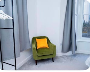 A corner room with a green armchair, a grey curtain, and a window with a view. - Central Cardiff Sleeps 6  Free Parking (Cardiff)