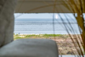 Vista desde el interior de una tienda o refugio hacia una playa con cielo despejado.