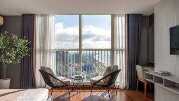 Une chambre d’hôtel moderne dotée d’un grand balcon, de deux chaises, d’une petite table, d’un lit et d’un téléviseur.